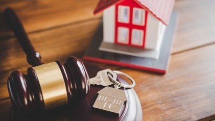 a gavel, home figurine, and house keys